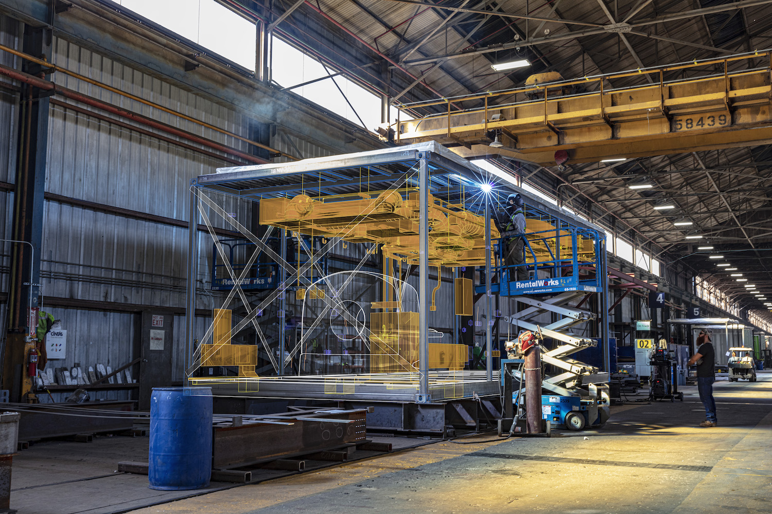 Men constructing modular units for a hospital building on a factory floor.