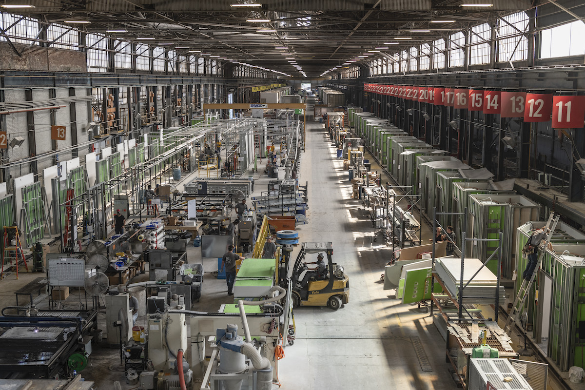 Men constructing modular units for a hospital building on a factory floor.