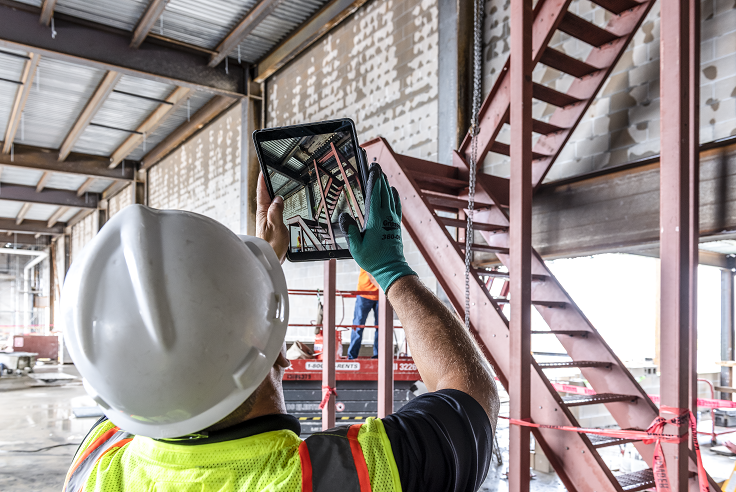 Construction worker looking at a project onsite through an iPad.