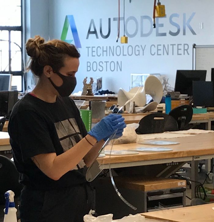 woman constructs a face shield 