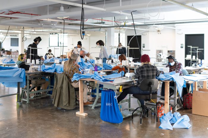 multiple people working at sewing machines in a large room