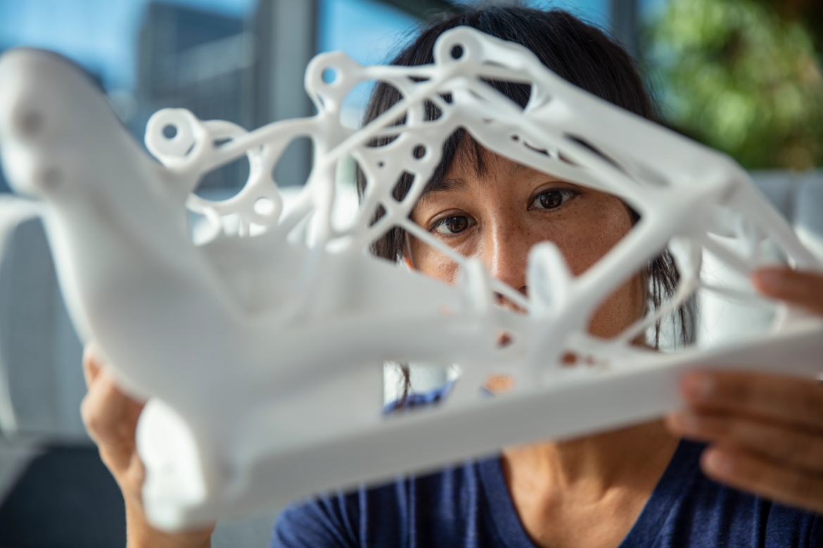An engineer examines a prototype 3D-printed part designed using the Autodesk Fusion 360 Generative Design Extension. 