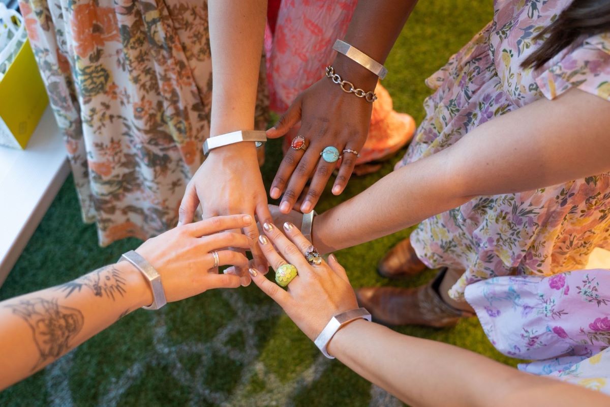 Hands posed together wearing jewelry designs