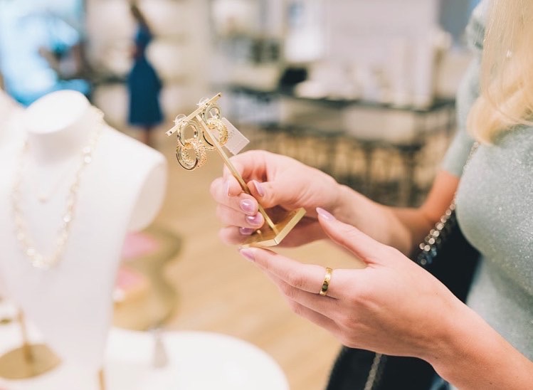 Hands holding gold hoop earing display