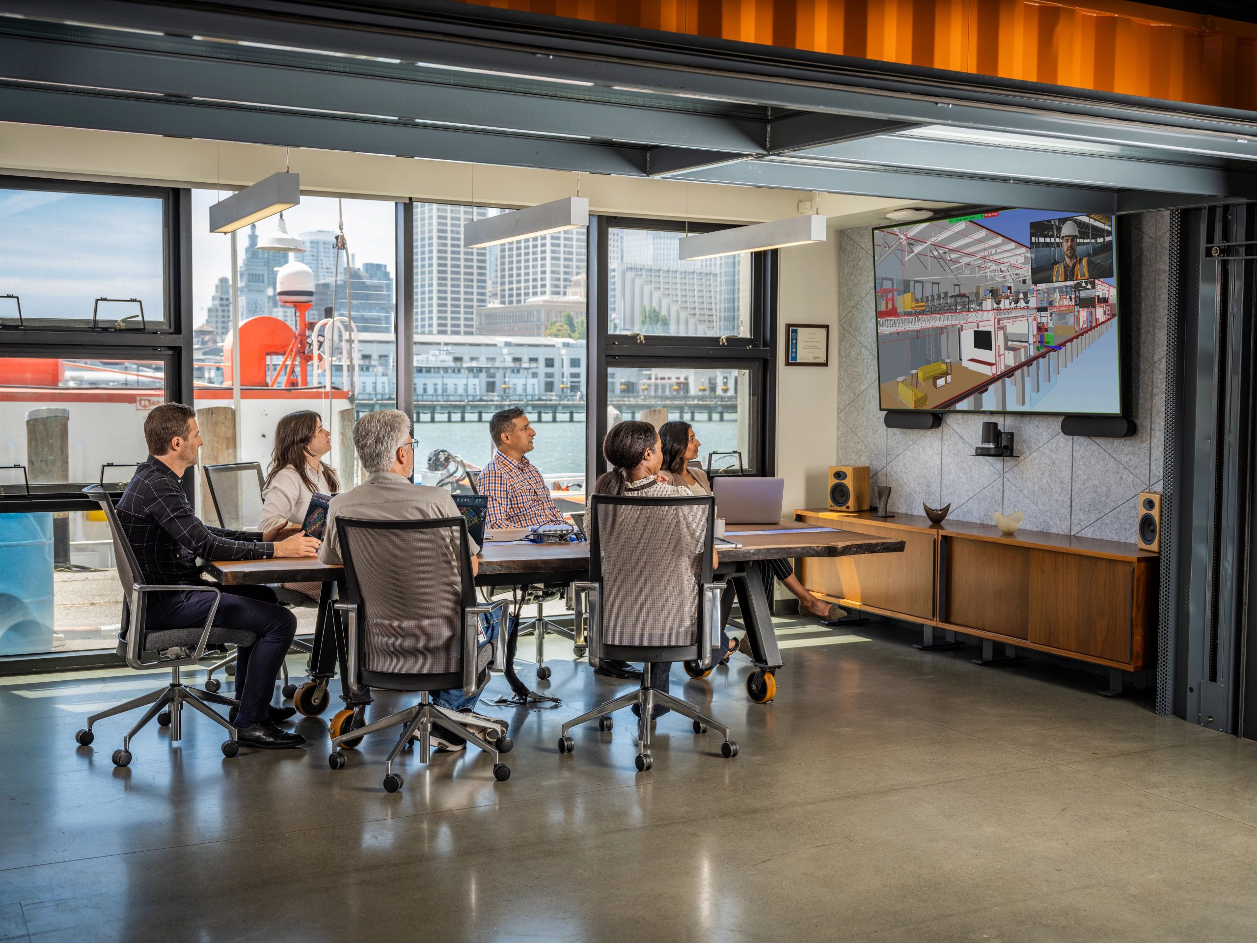 6 people in a meeting room looking at a screen