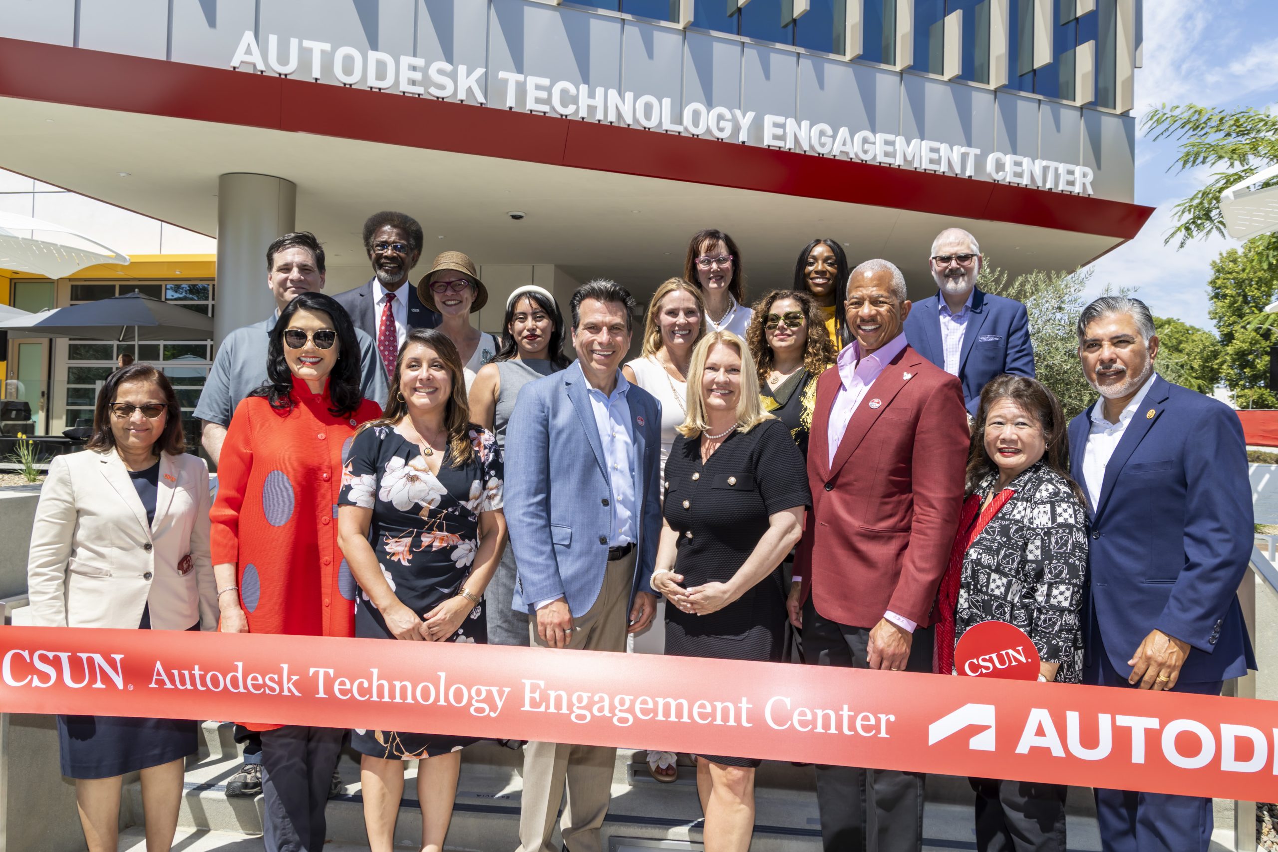 A group of people in front of a ribbon in front of the Autodesk Technology Engagement Center