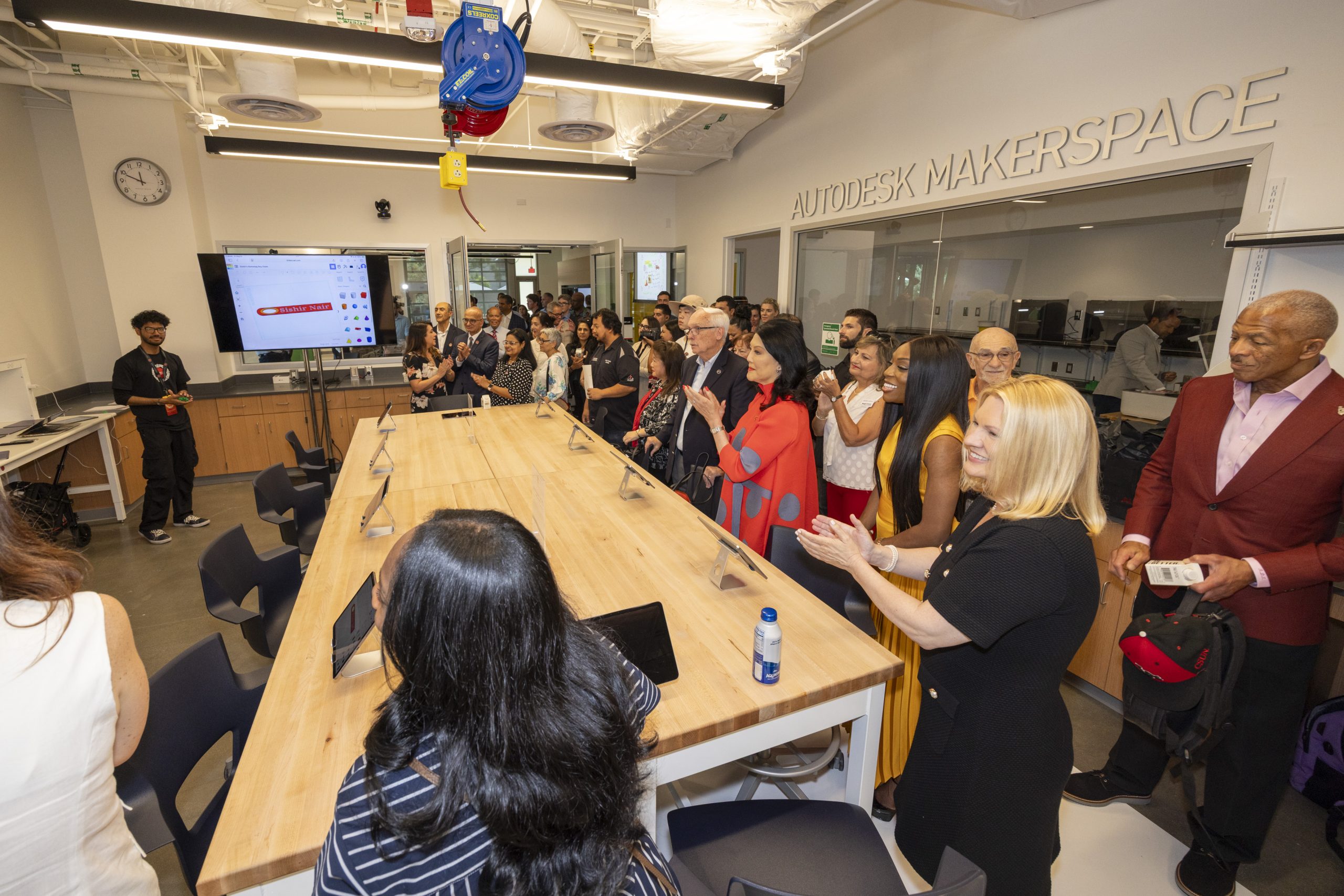 people around a table in the Autodesk Makerspace clapping